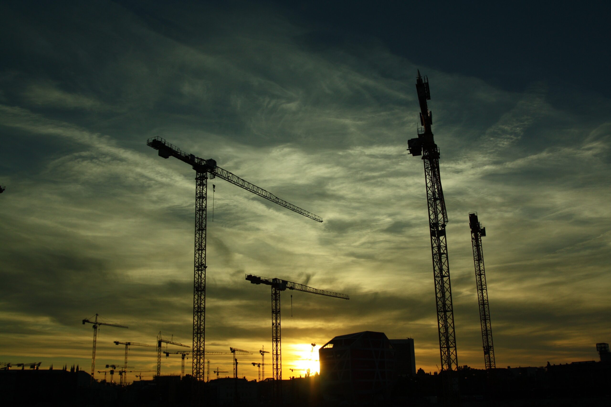 Construction site with several tower cranes at sunset