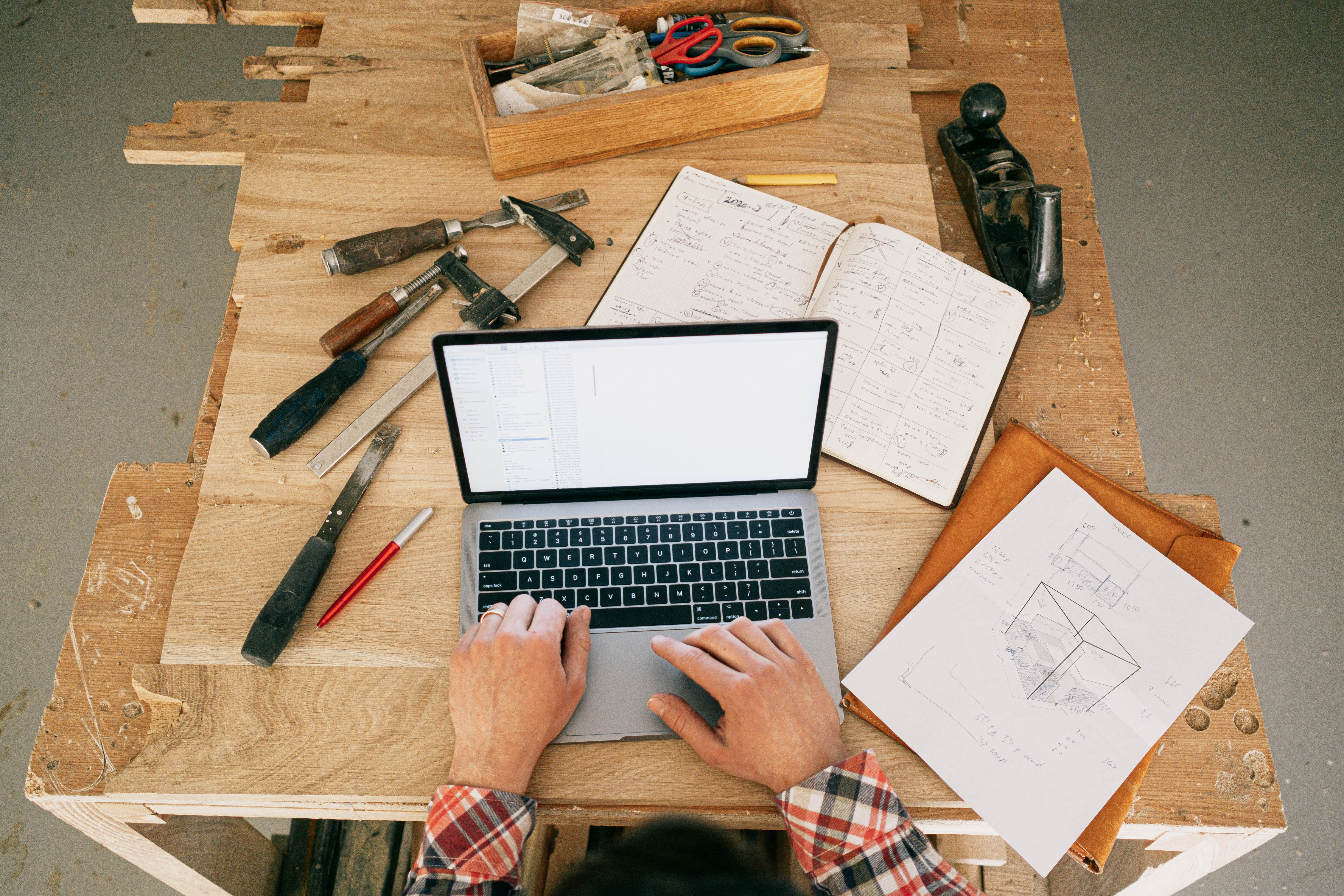 Person working on a laptop at a table with engineering tools